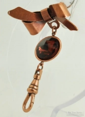 Base metal bow style lapel pin with a faceted purple rhinestone and an engraved swivel clasp