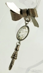 Base metal bow style lapel pin with a faceted crystal clear rhinestone and an engraved swivel clasp